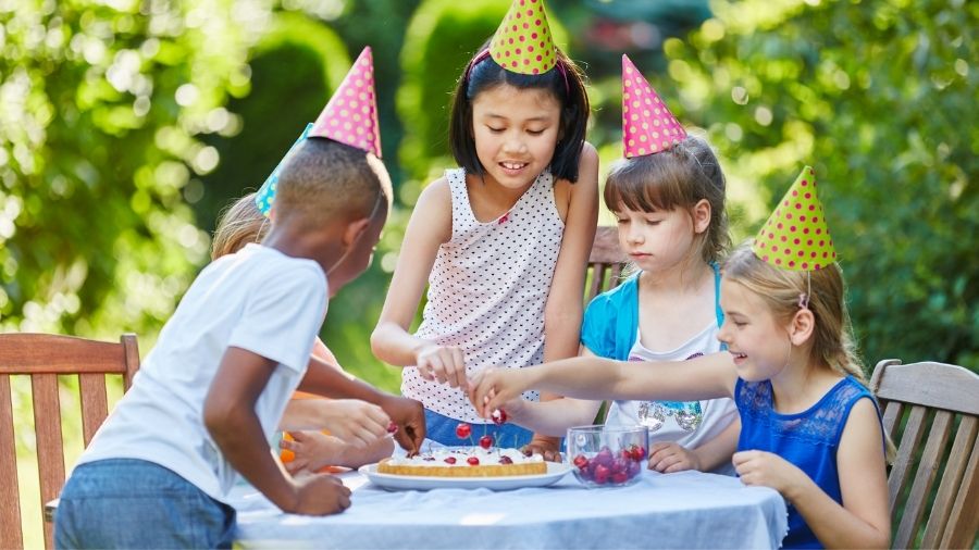 Kids at a birthday party putting cherry on a pie