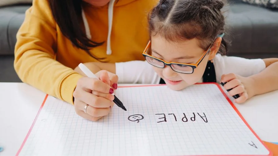 Woman teaching girl how to write